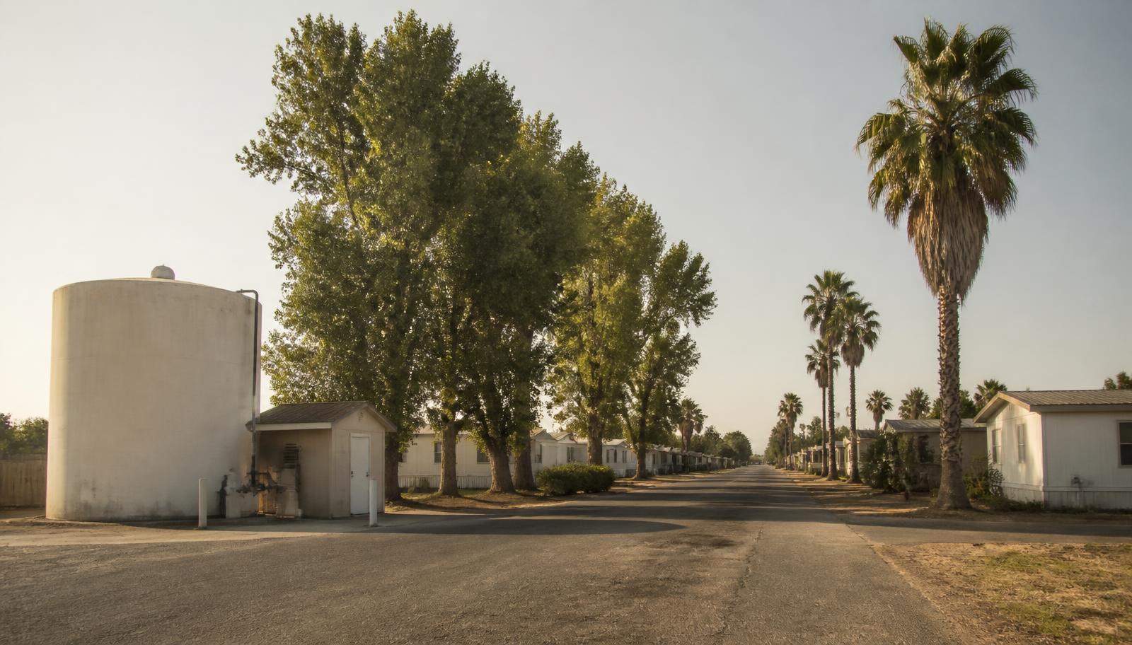 Water storage tank and small pump building at the edge of a rural Central Valley mobile home community